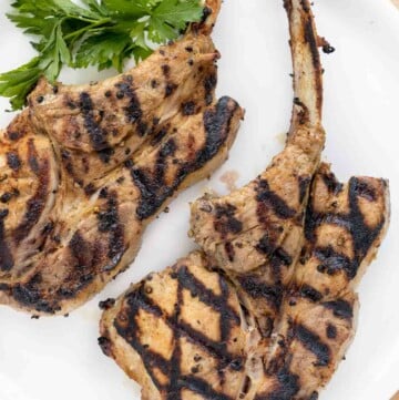 2 grilled pork chops on a white plate