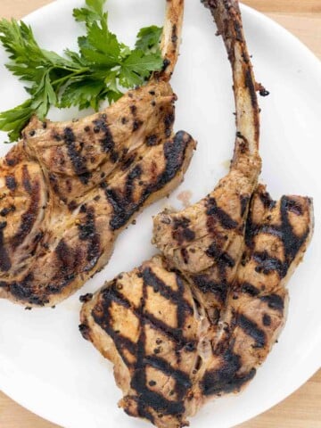 2 grilled pork chops on a white plate