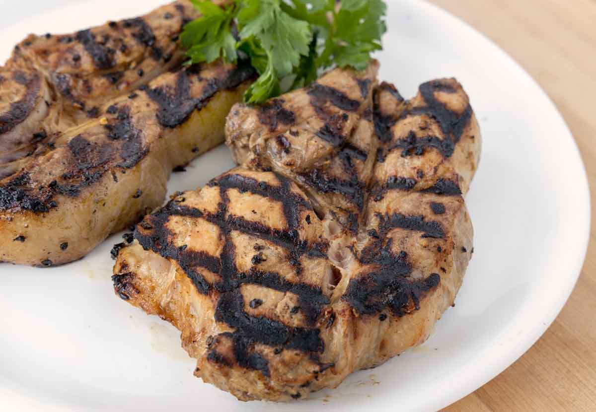 2 grilled marinated pork chops on a white plate