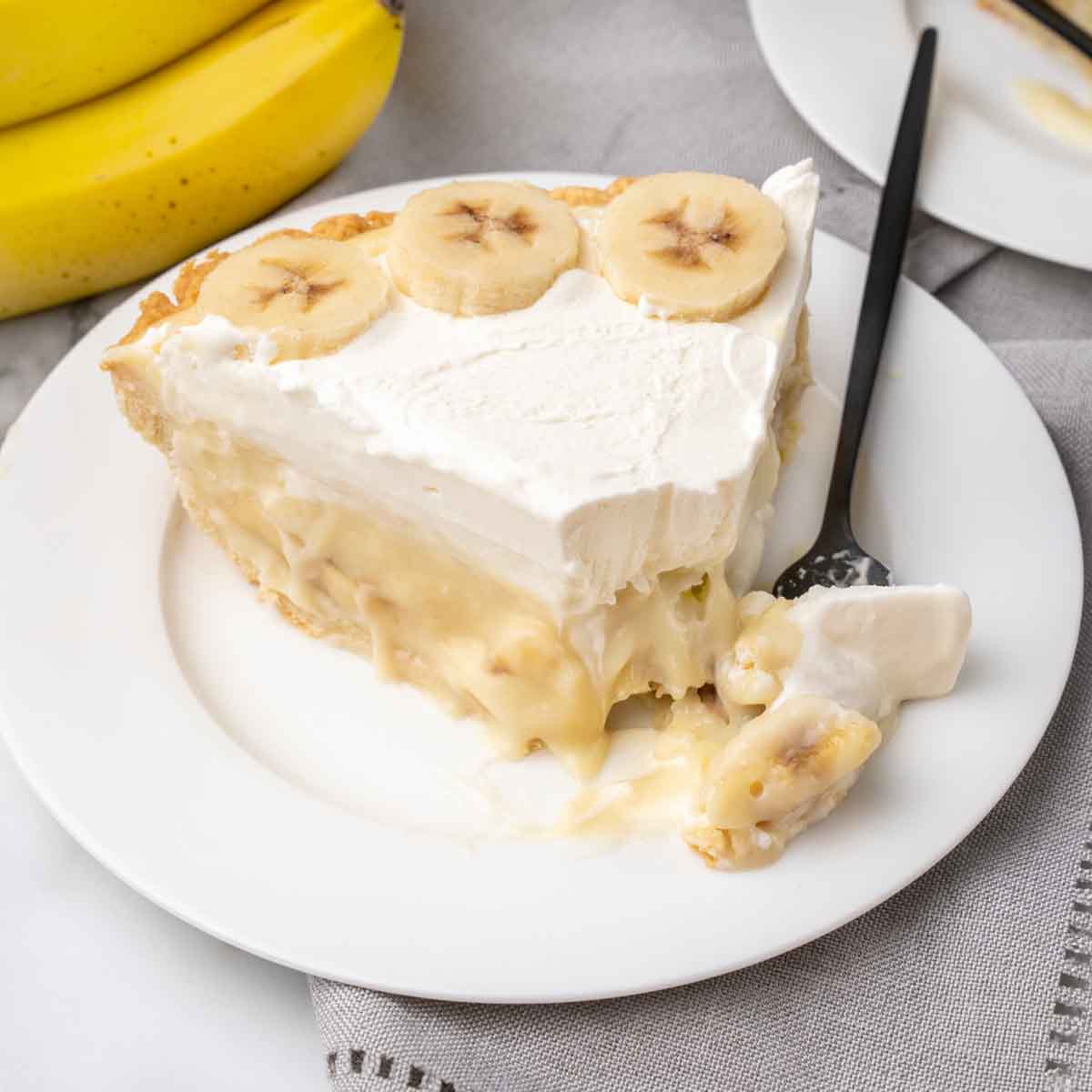 slice of banana cream pie with fork taking out a piece.