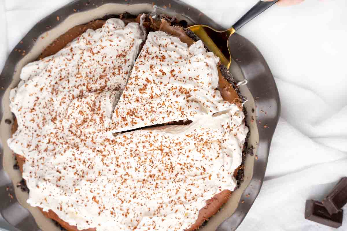 whole french silk pie with a slice being taken out of it with a pie spatula