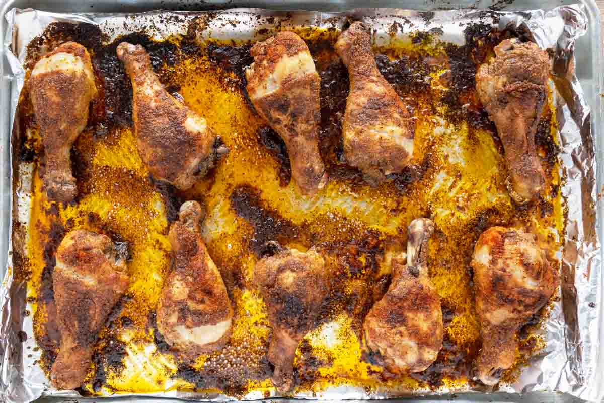 baked seasoned chicken legs on a foil lined tray