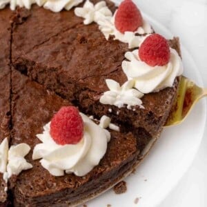 slice of flourless chocolate cake being taken. out of whole cake