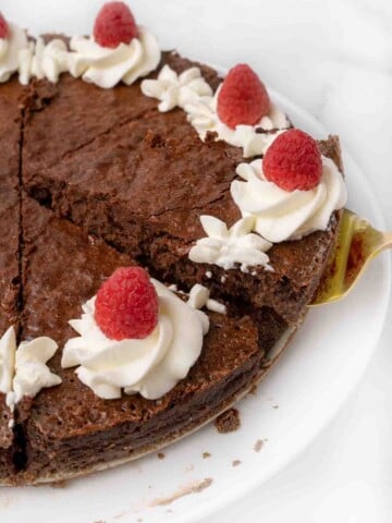 slice of flourless chocolate cake being taken. out of whole cake