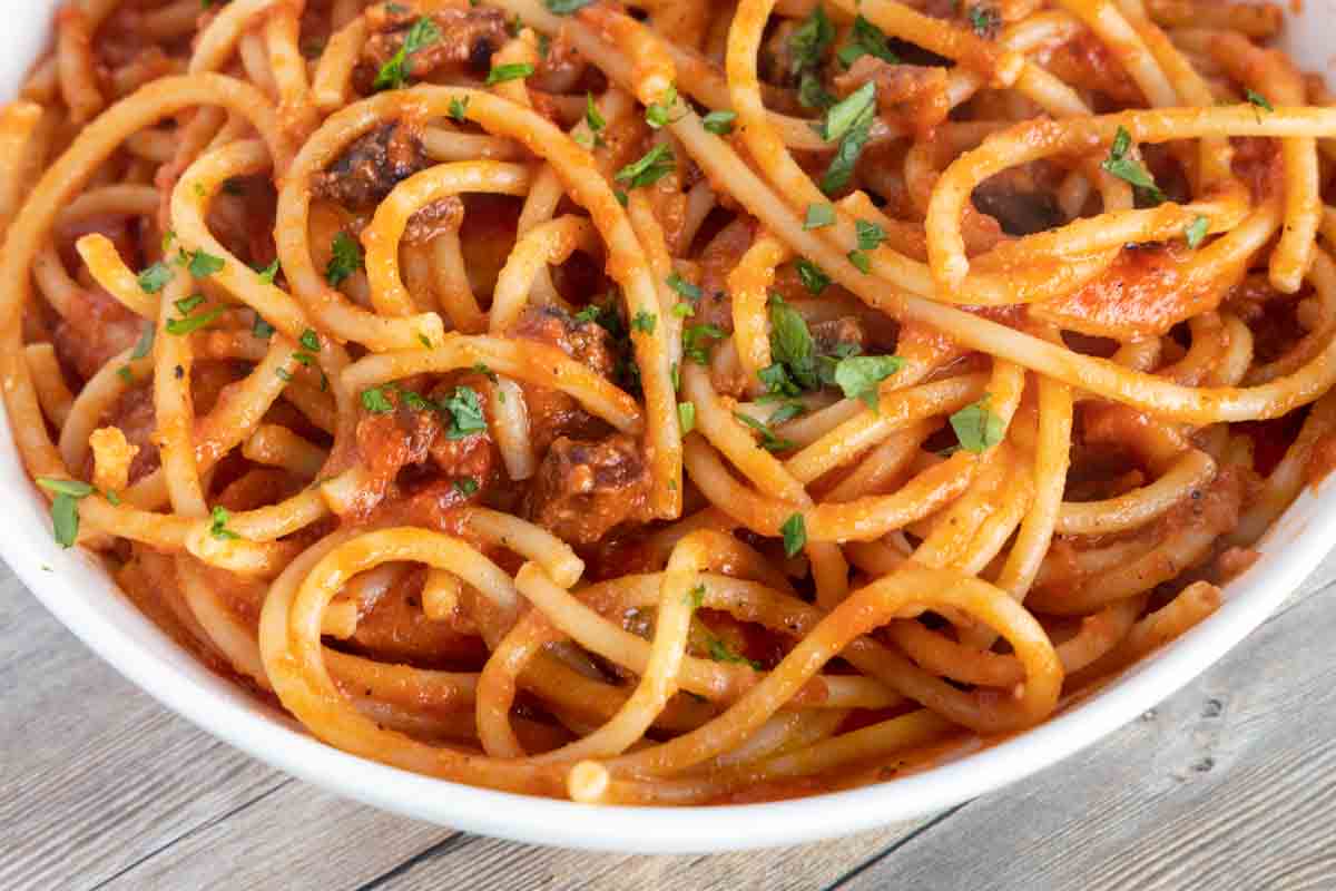 close up of bucatini all amatriciana in a white bowl