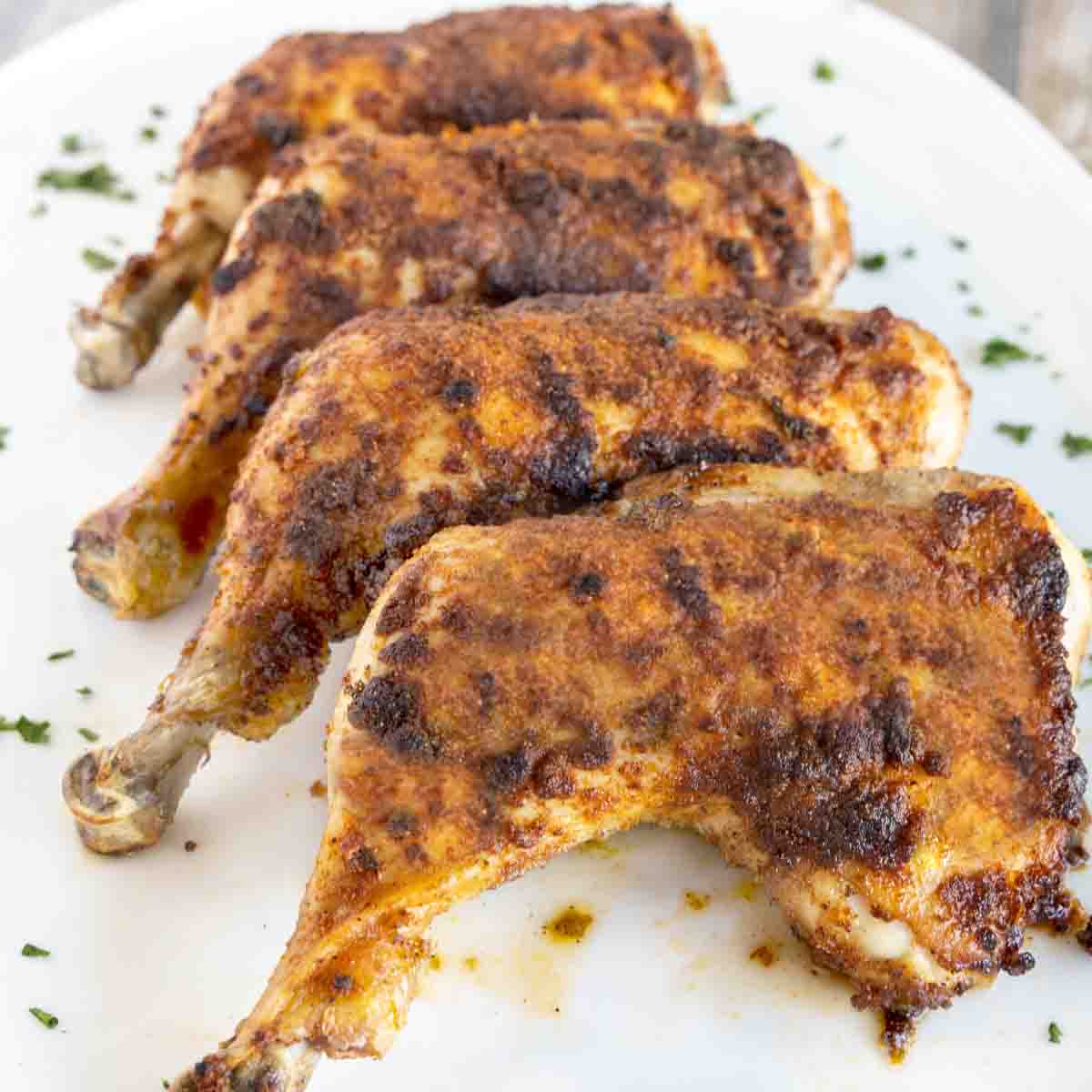 4 baked chicken leg quarters on a white platter.