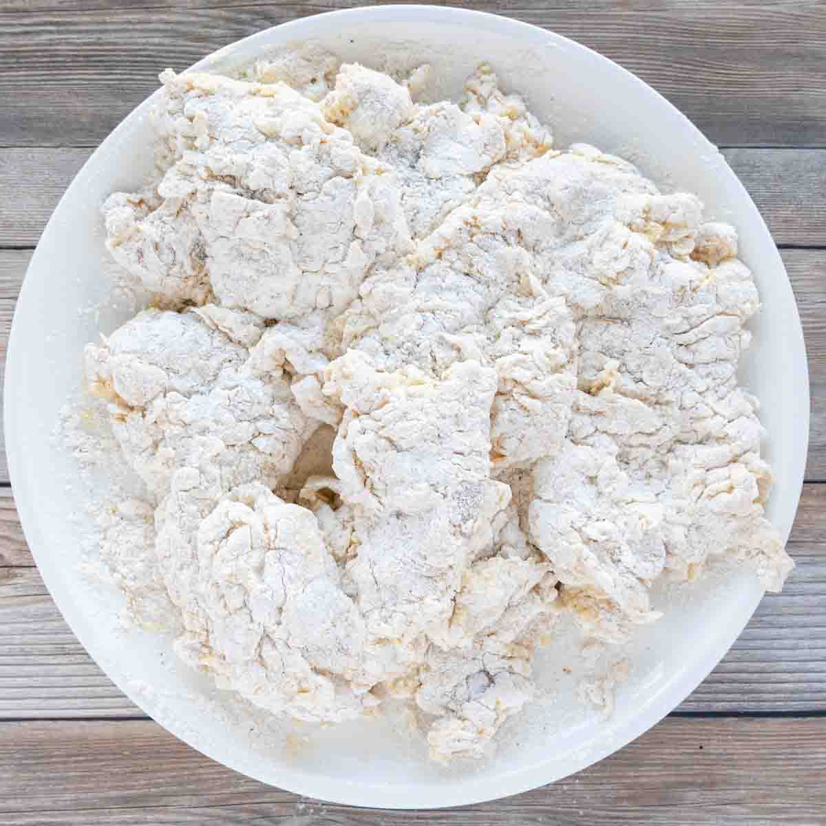 floured chicken on a white plate