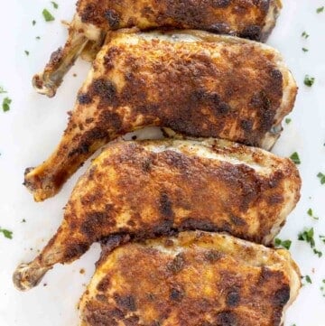 crispy seasoned chicken leg quarters on a white platter