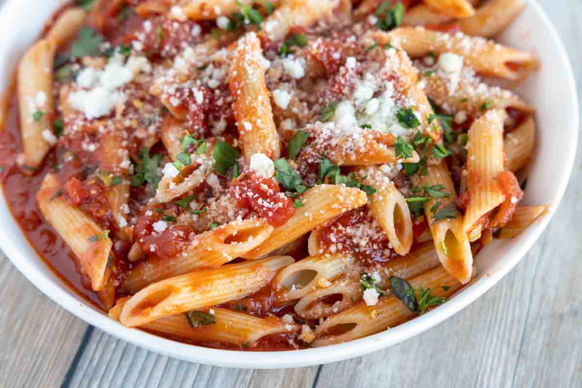 close up of penne arrabbiata in a white bowl