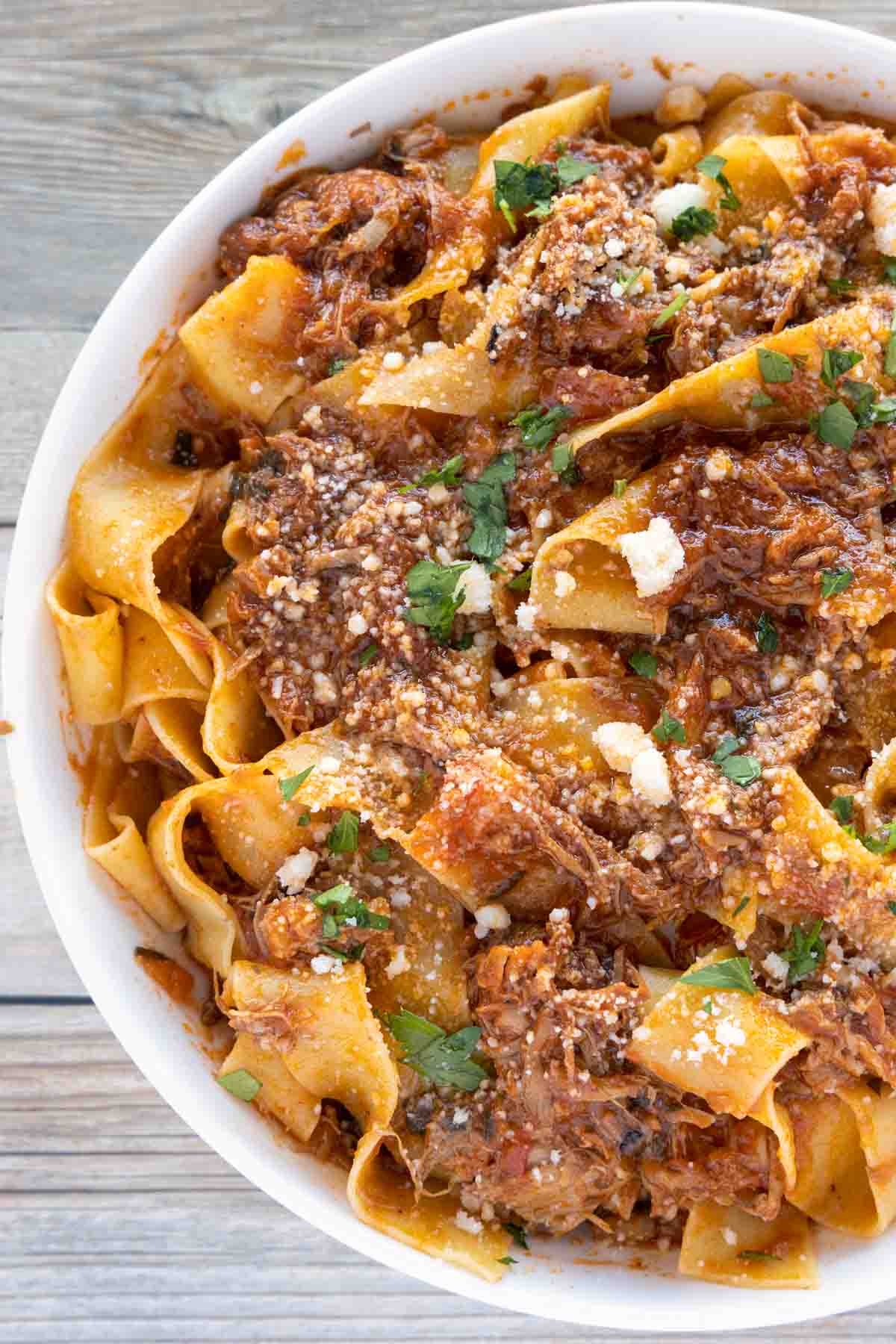 partial view of ragu napoletano over pappardelle in white bowl