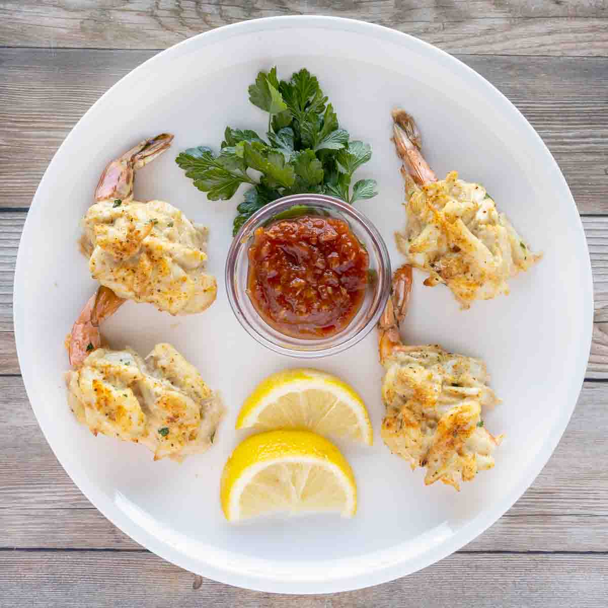 Stuffed Shrimp on a white plate with cocktail sauce and lemons