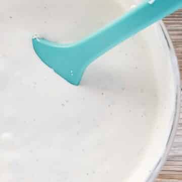 glass bowl of bleu cheese dressing with a blue rubber spatula in the bowl