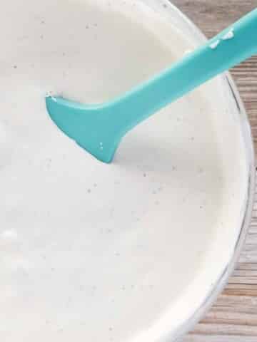 glass bowl of bleu cheese dressing with a blue rubber spatula in the bowl