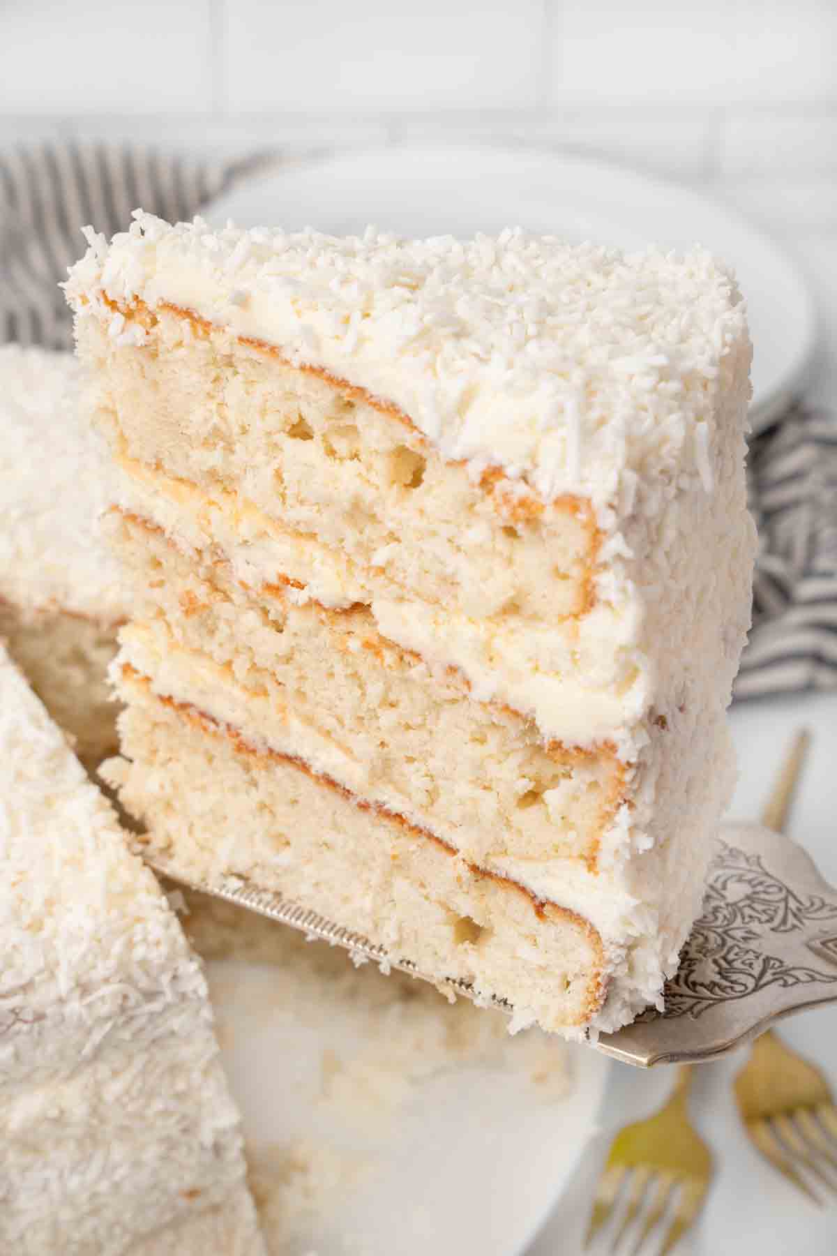 coconut cake on spatula being taken out of whole cake.