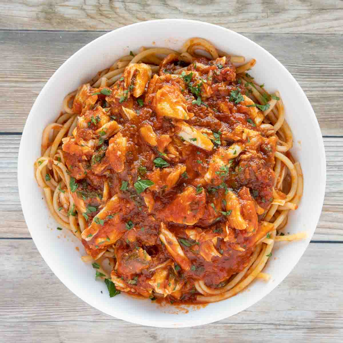 overhead shot of pasta with red crab sauce in white bowl