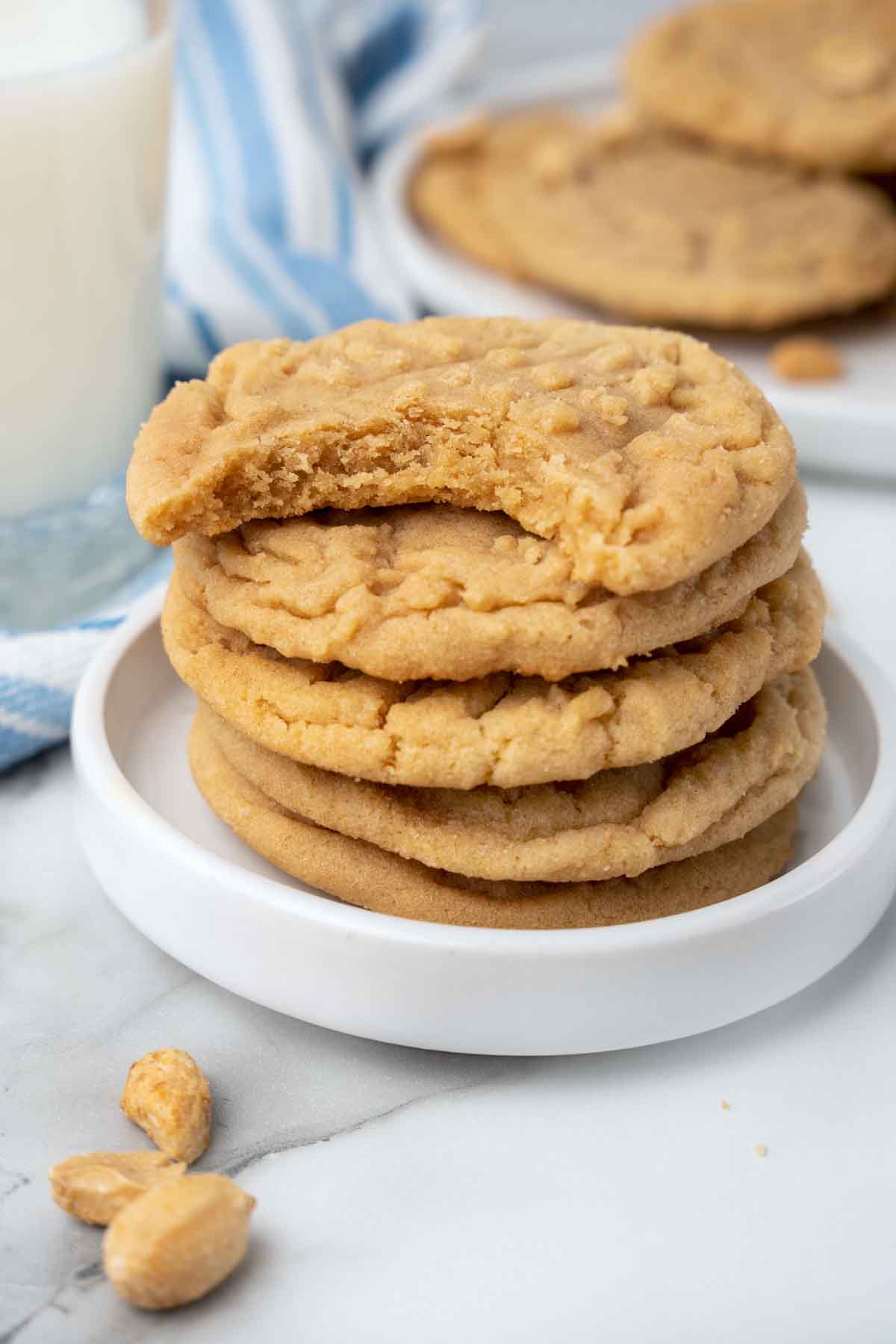 stack of peanut butter cookies on a white plate with a bite taken out of the top cookie