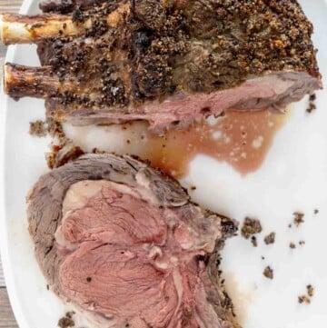 cut of rare prime rib next to roast on white platter