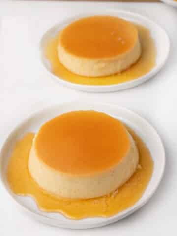 2 white plates with flan and caramel sauce