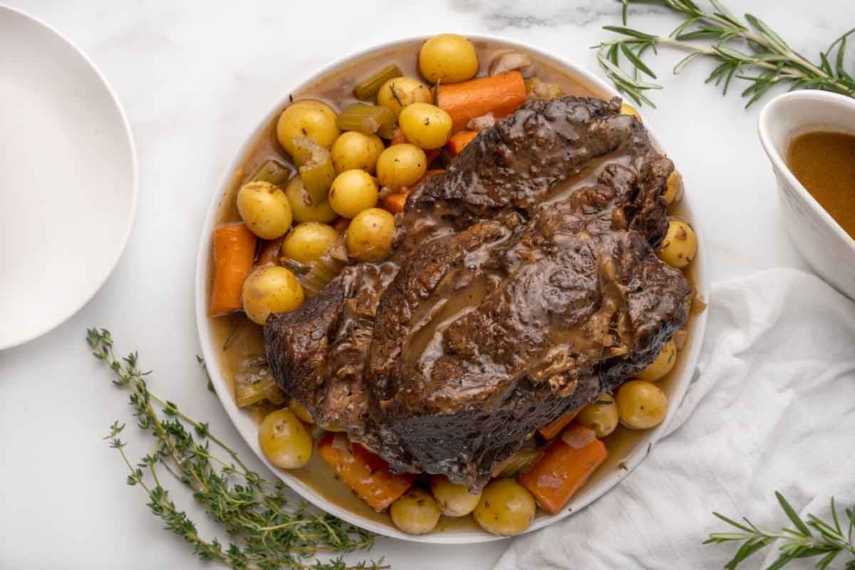 cooked pot roast with potatoes and carrots on a white plate