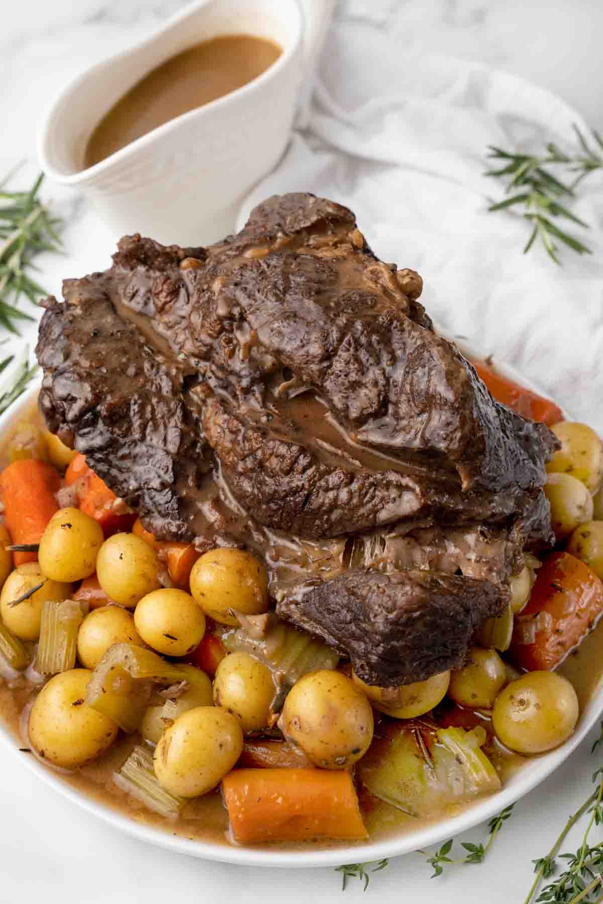 whole pot roast with potatoes and carrots on a white platter