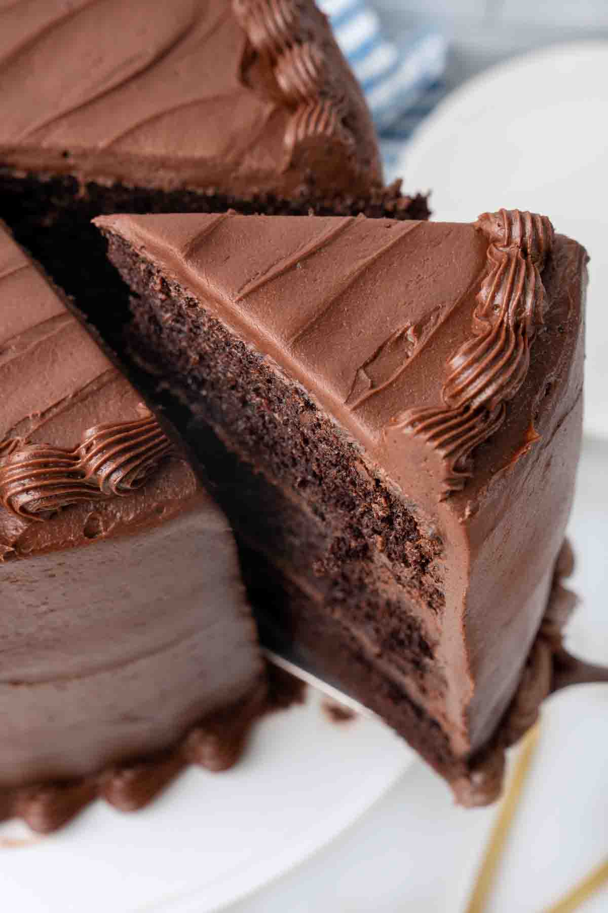 slice being taked out of a chocolate cake on a white platter