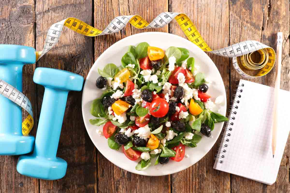 barbells, salad, notebook and tape measure