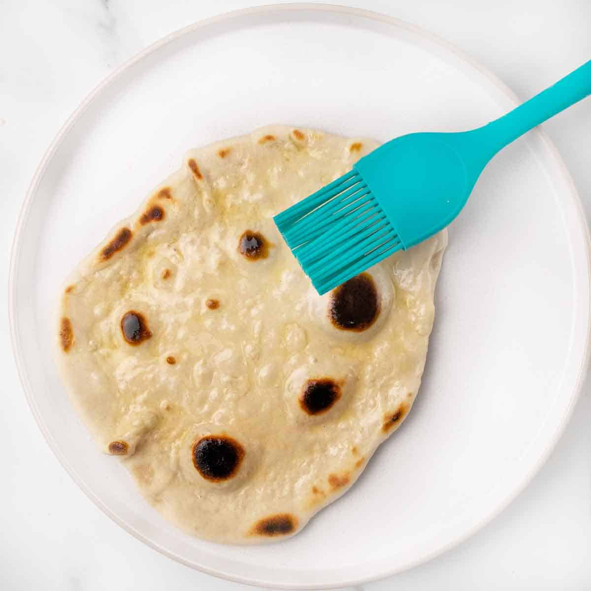 buttering naan bread with blue silicone brush.