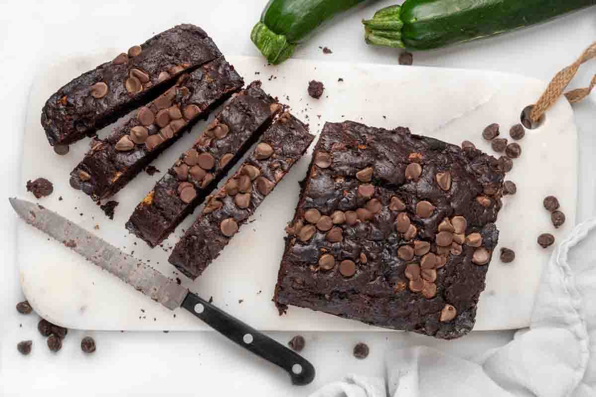chocolate zucchini bread sliced with knife on white cutting board.