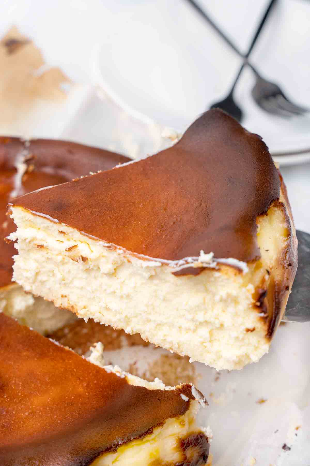 slice of basque cheesecake being taken out of the whole cheesecake