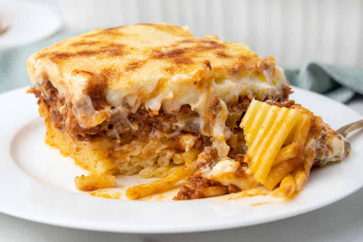 slice of pastitsio on a white plate with a fork