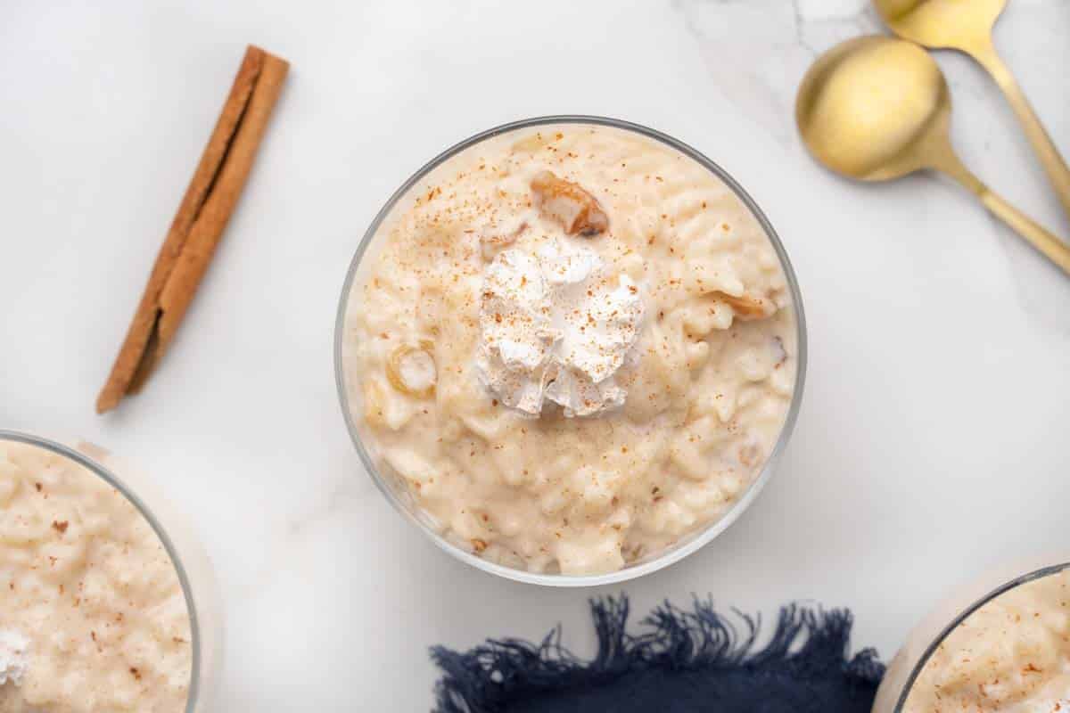 overhead view of rice pudding in a dessert glass with a cinnamon stick along side.