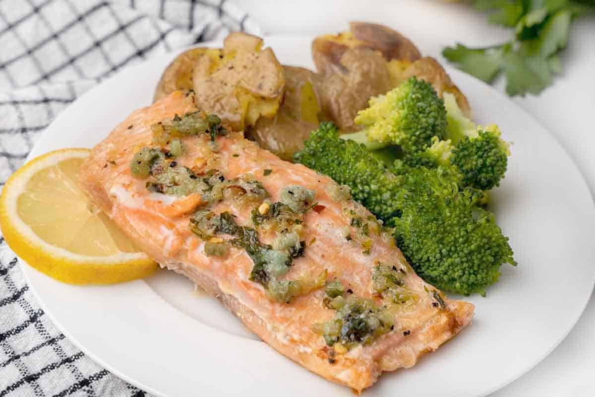 garlic butter salmon with potatoes and broccoli on a white plate