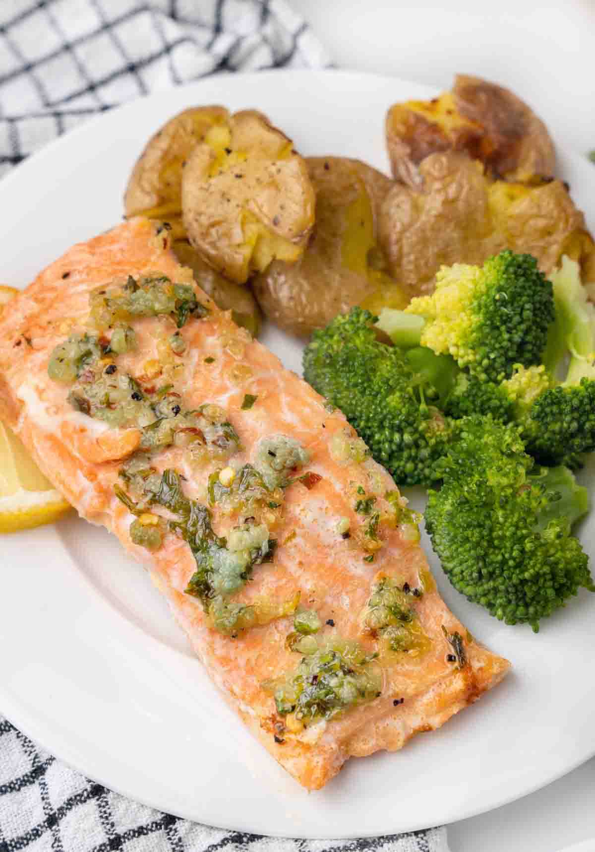 garlic butter salmon with broccoli and potatoes on a white plate