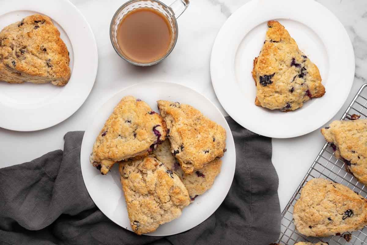 blueberry scones on white plates with a cup of coffee on a table