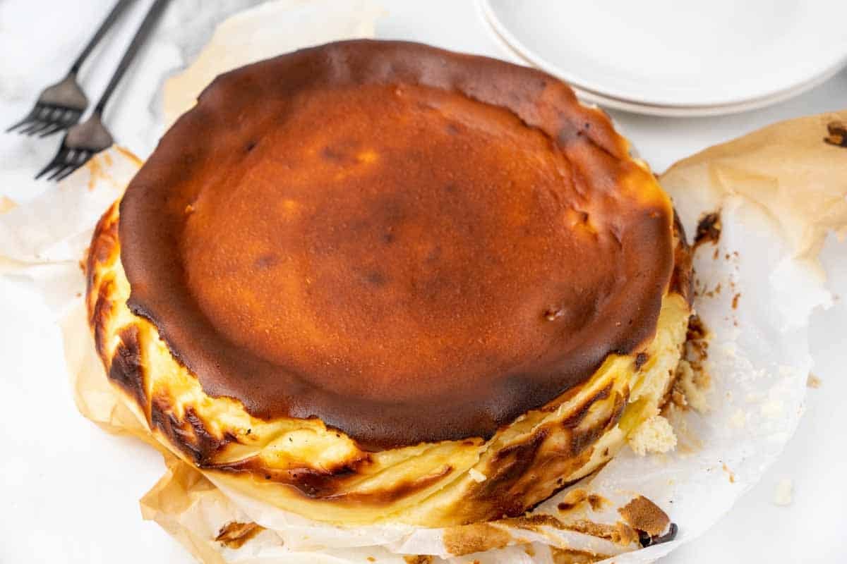 basque cheesecake removed from springform pan with parchment around cake