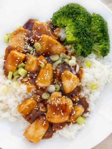 Korean BBQ Chicken over jasmine rice on a white plate with broccoli.