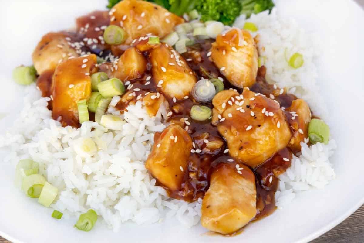 Korean BBQ Chicken over jasmine rice on a white plate.