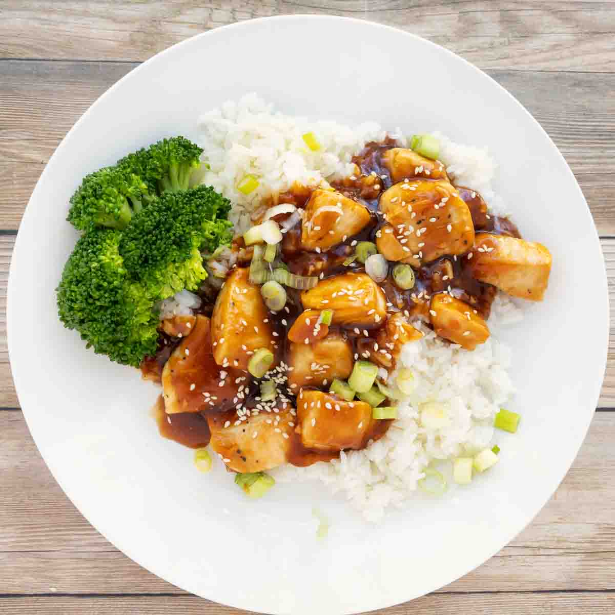 Korean BBQ Chicken over jasmine rice on a white plate with broccoli.