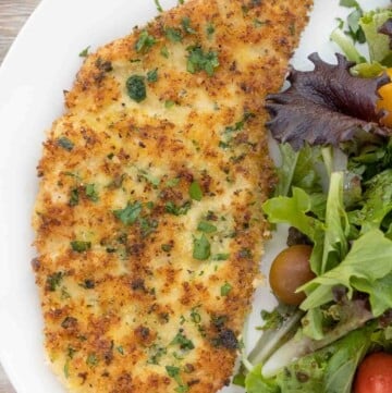 Chicken Milanese with salad on a white plate