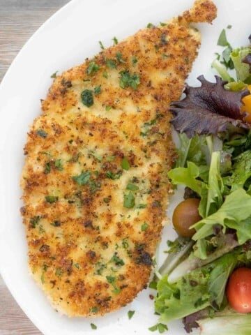 Chicken Milanese with salad on a white plate
