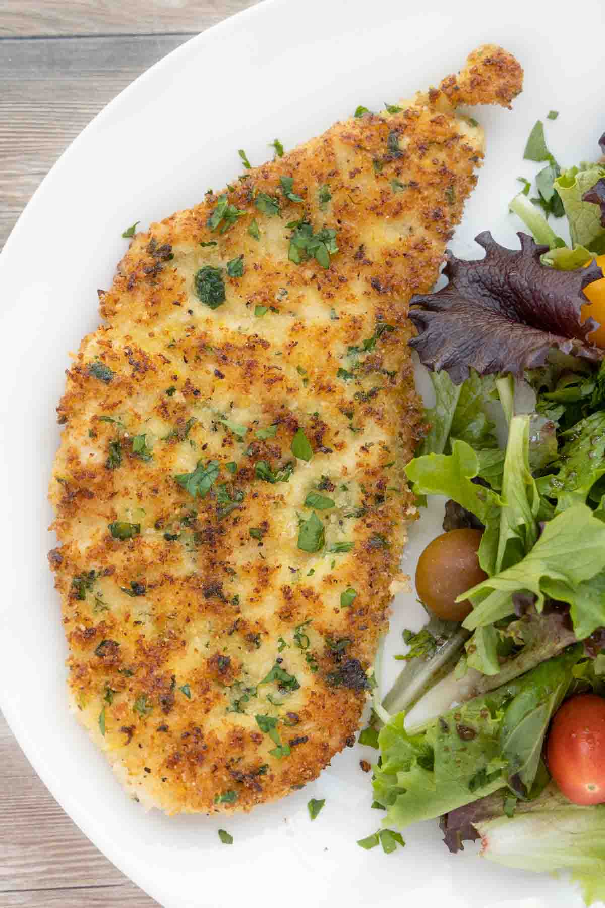 Chicken Milanese with salad on a white plate