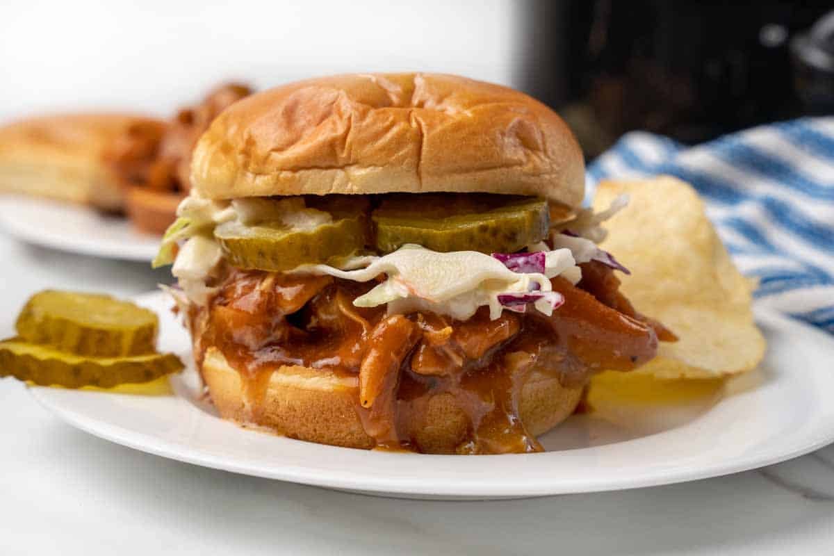 bbq chicken sandwich with cole slaw and pickles on bun.