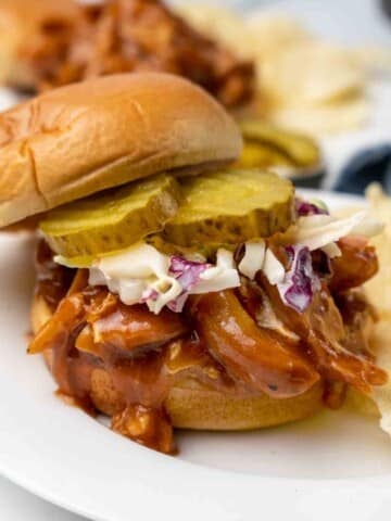 bbq chicken sandwich with cole slaw and pickles on bun.