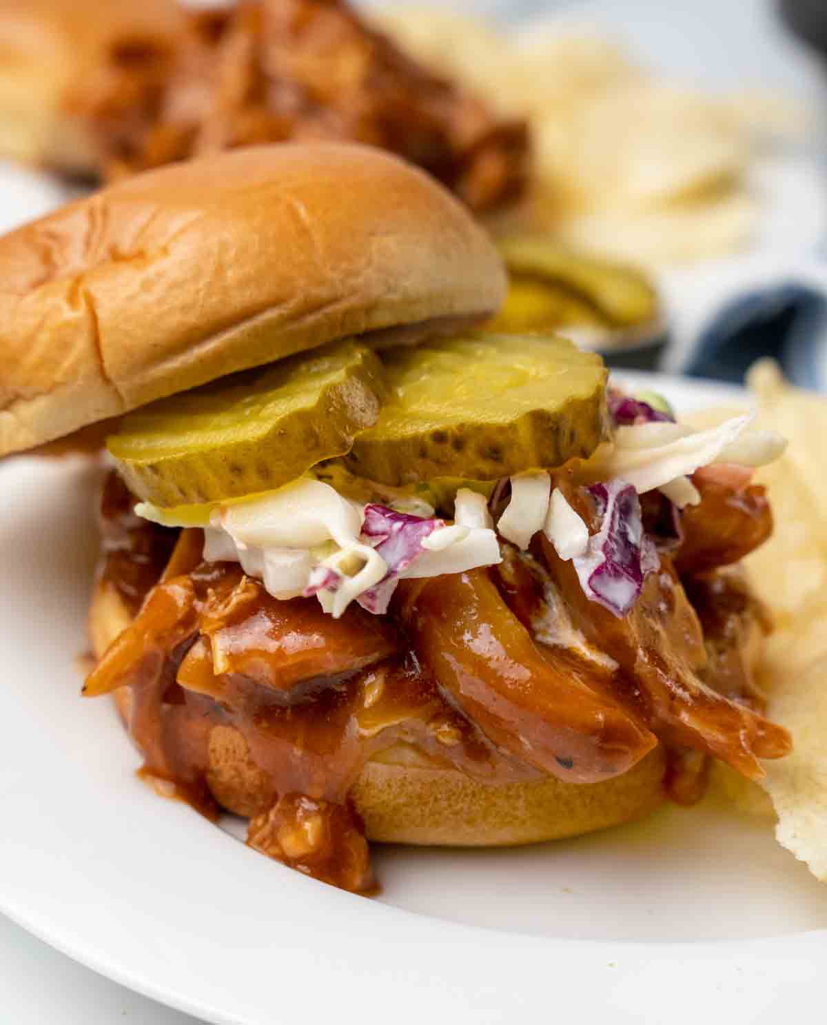 bbq chicken sandwich with cole slaw and pickles on bun.