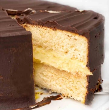 slice of boston cream pie being taken our of whole cake