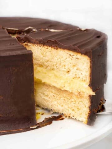 slice of boston cream pie being taken our of whole cake