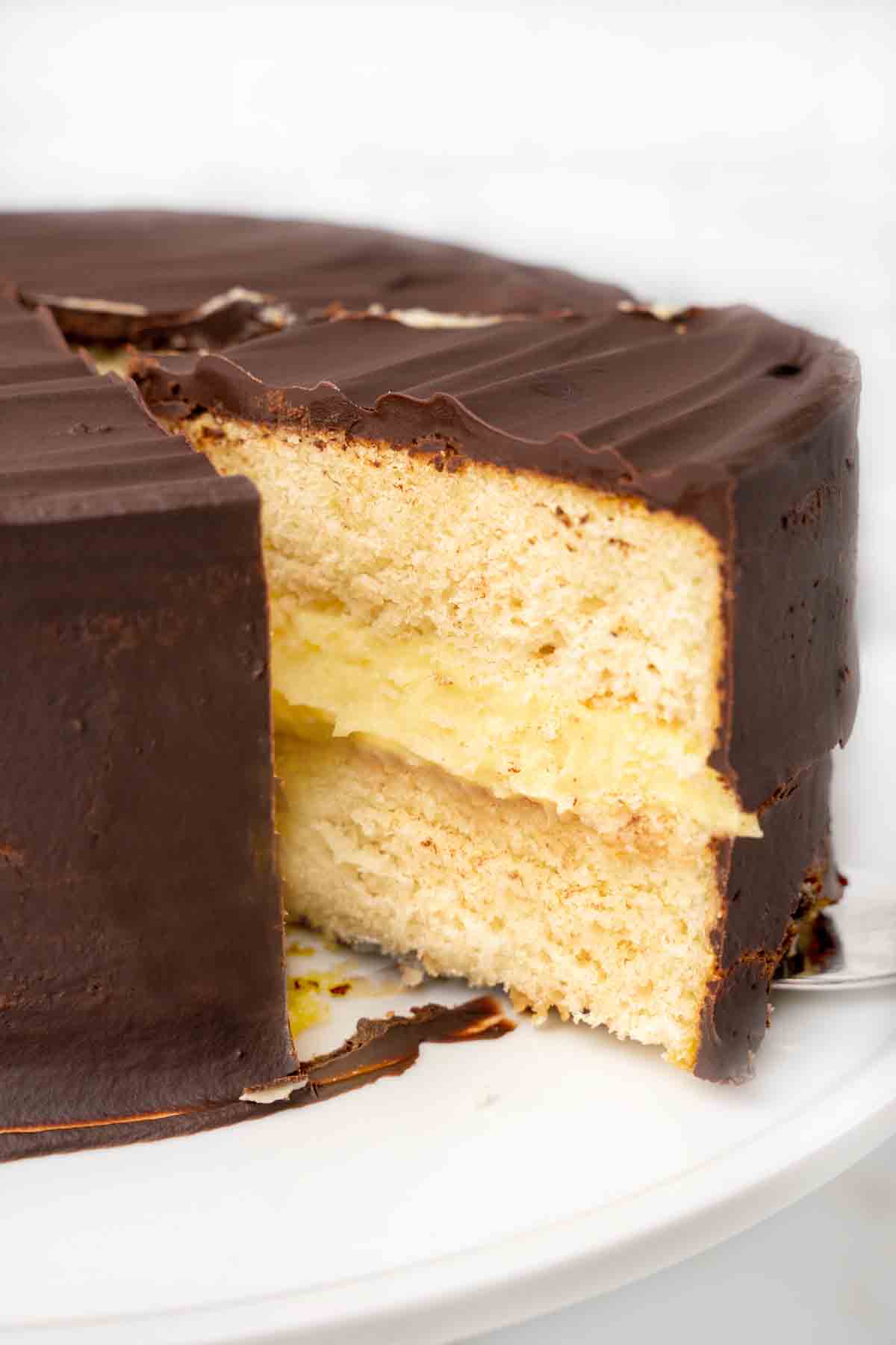slice of boston cream pie being taken our of whole cake