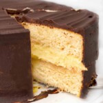 slice of boston cream pie being taken out of whole cake.