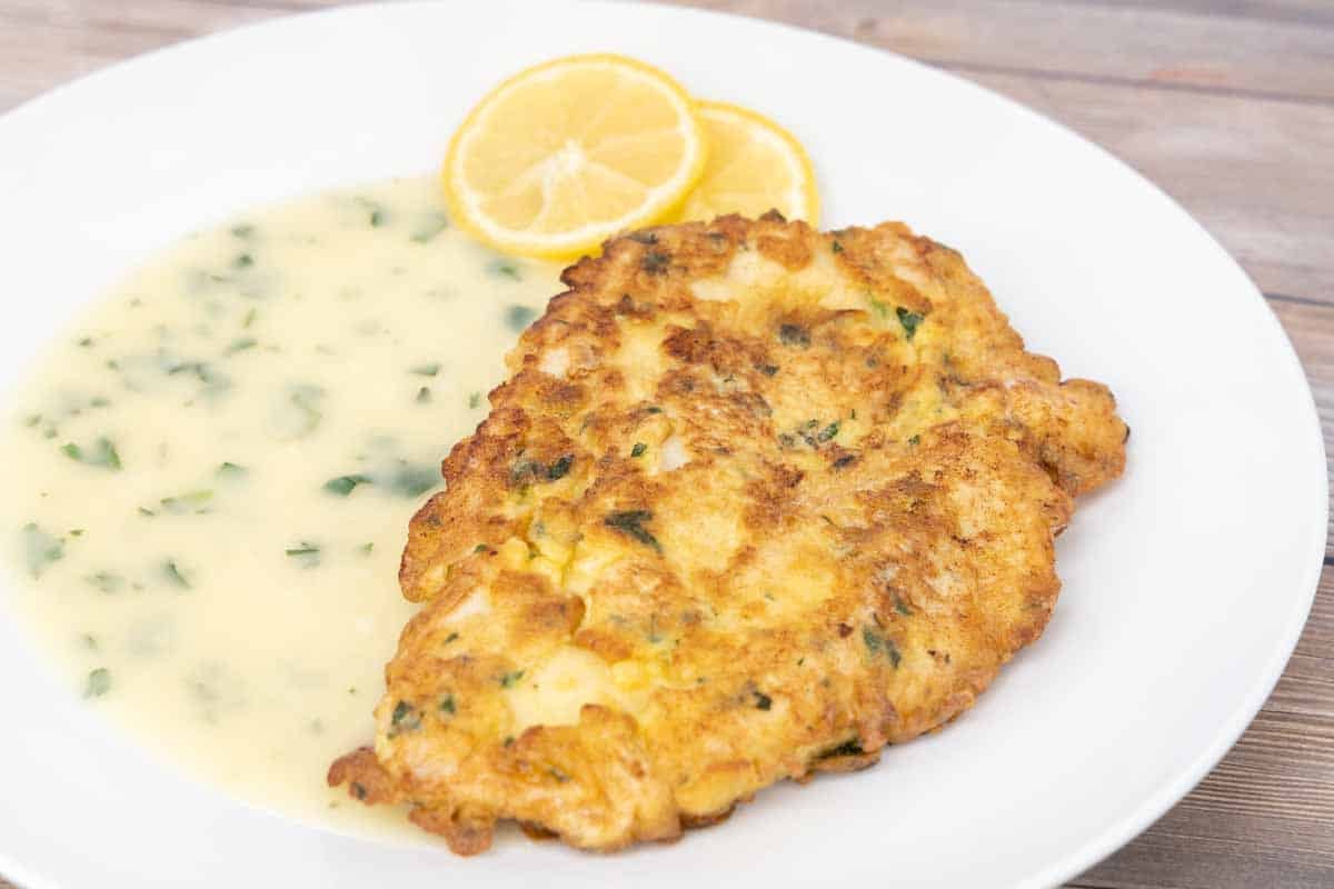 chicken francaise with lemon butter sauce on white plate.