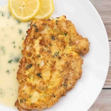 chicken francaise with lemon butter sauce on white plate.